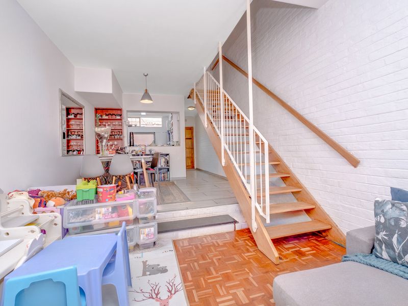 Open plan living area featuring a wooden staircase, mixed flooring types, and built-in shelving, creating a functional multi-level layout.