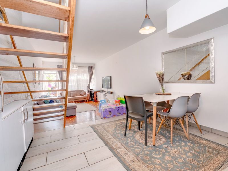 Open-plan living and dining area featuring a modern staircase, tiled flooring, and neutral finishes, creating a bright and functional space.