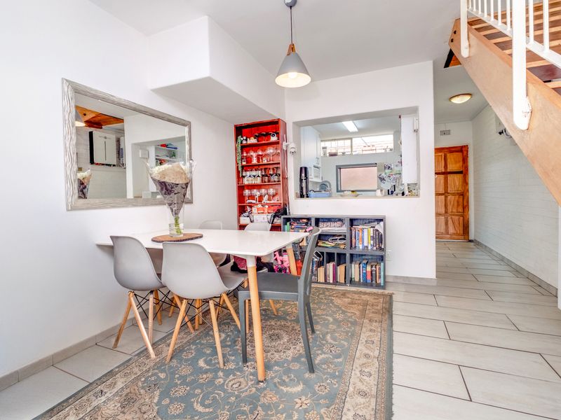 Open plan dining area featuring tiled flooring, a staircase, and a convenient pass-through window connecting to the kitchen space.