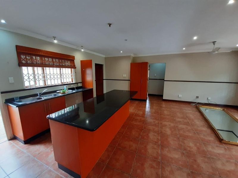 Spacious open-plan kitchen featuring granite countertops, ample built-in cabinetry, and tiled flooring, offering a functional layout ready for modern updates.