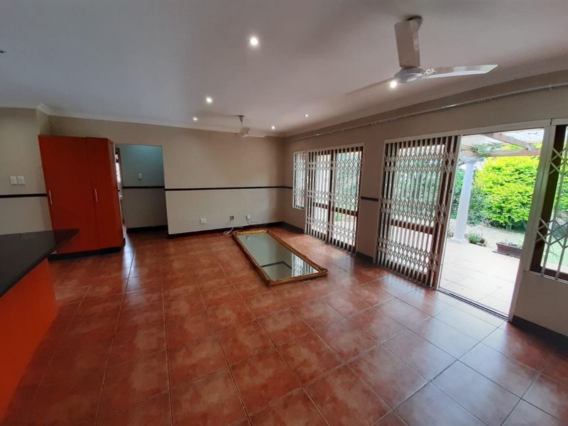 Spacious open-plan living area featuring ceramic tile flooring, recessed lighting, ceiling fans, and large sliding doors providing direct access to the outdoor patio.