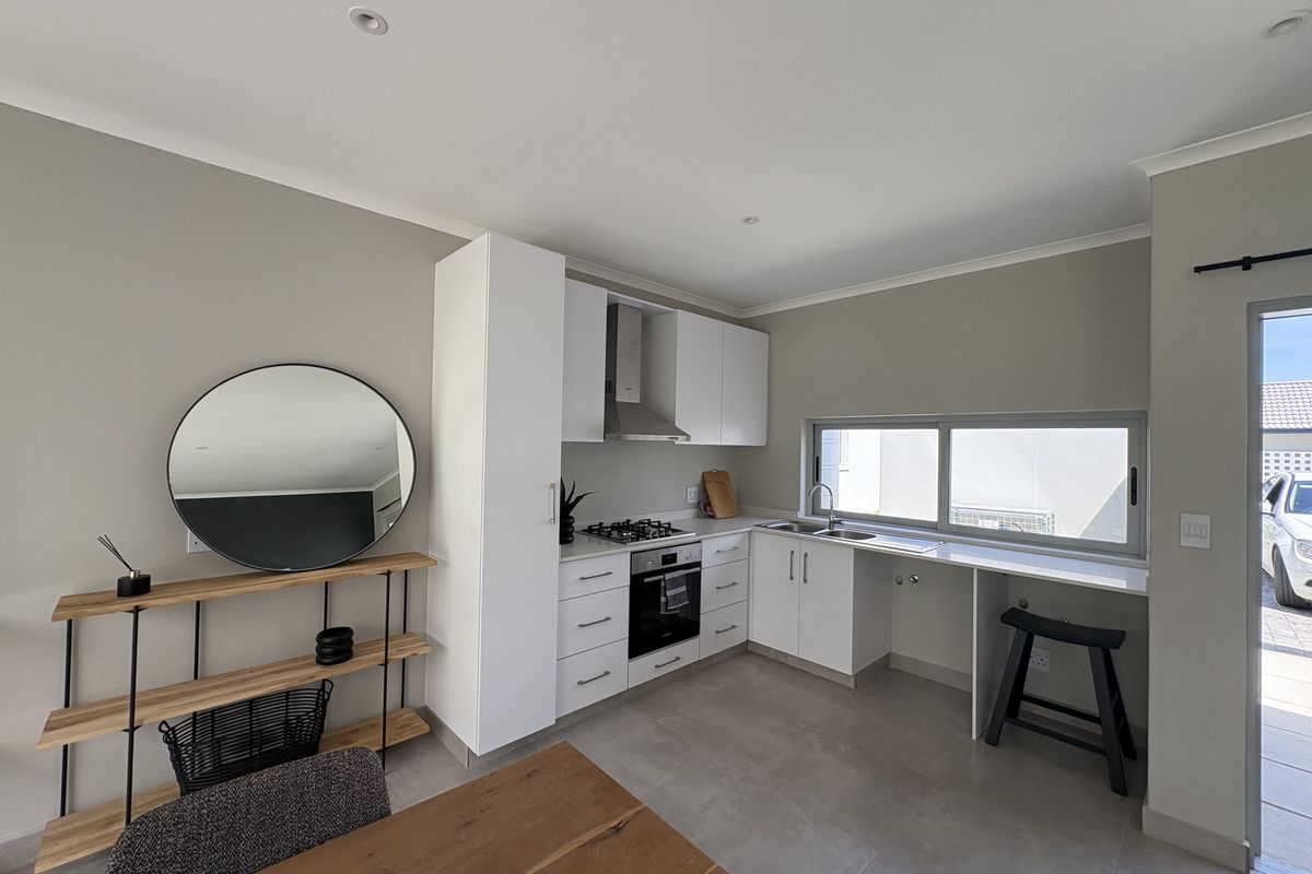Modern kitchen featuring white cabinetry, gas hob, extractor fan, under-counter oven, and tiled flooring with direct access to the exterior.
