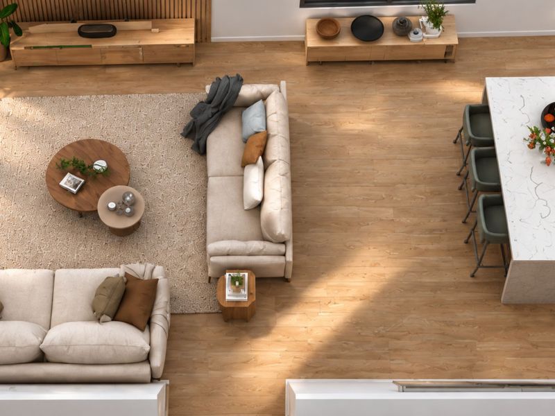 An overhead view of a modern open-plan living and kitchen area featuring wood-look flooring, a large marble-topped kitchen island, and decorative timber wall paneling.