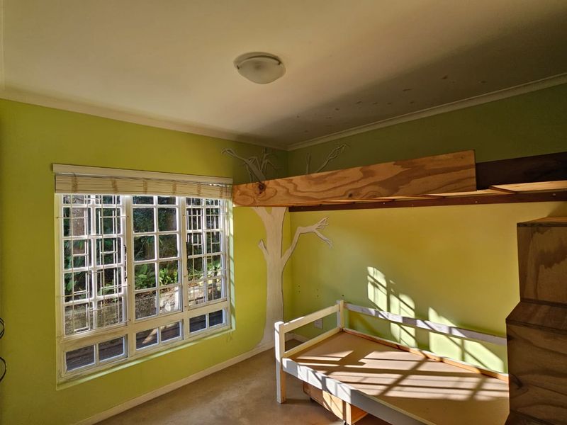 A bedroom featuring a multi-pane window with security bars and a custom built-in bunk bed structure, requiring cosmetic updates to the walls and ceiling.