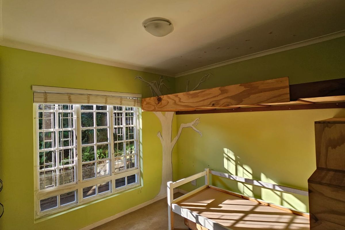 A bedroom featuring a multi-pane window with security bars and a custom built-in bunk bed structure, requiring cosmetic updates to the walls and ceiling.