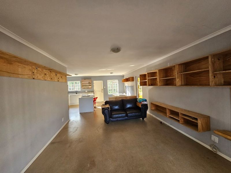 Open plan living and kitchen area featuring built-in wooden shelving units and a central kitchen island with cabinetry.