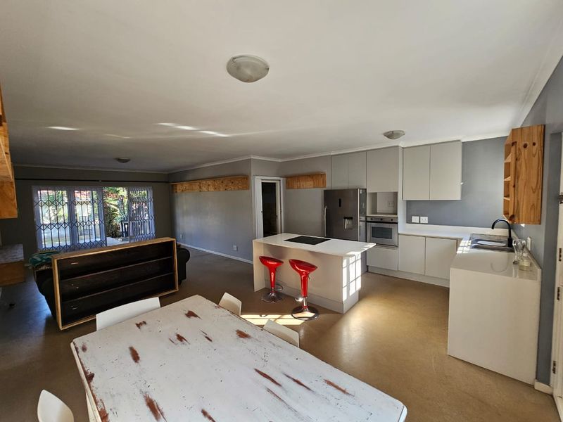 Spacious open-plan living and kitchen area featuring a central island, modern cabinetry, built-in oven, and direct access to the outdoor patio through sliding doors.