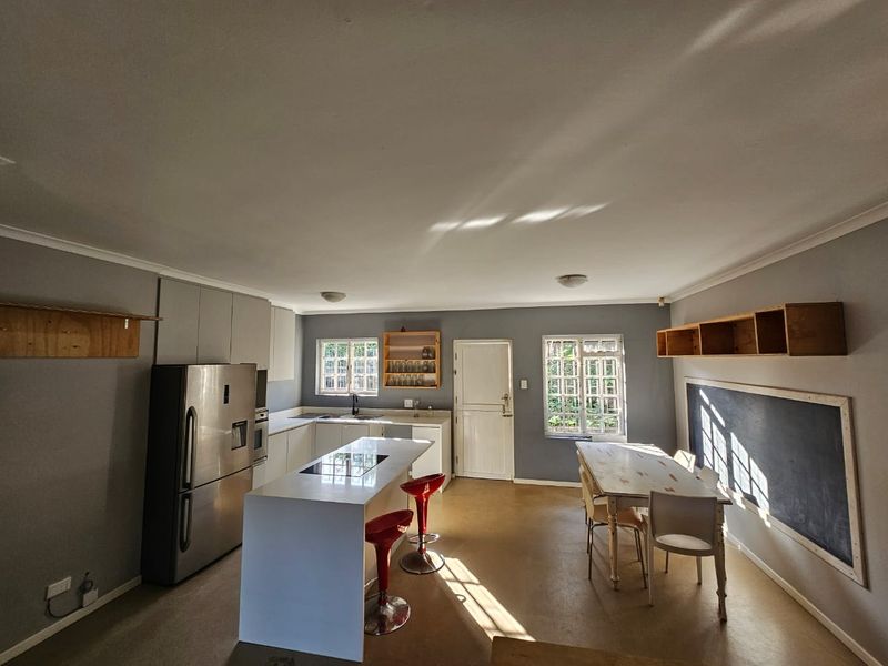 Spacious open-plan kitchen and dining area featuring a central island, modern cabinetry, and ample natural light through multiple windows.
