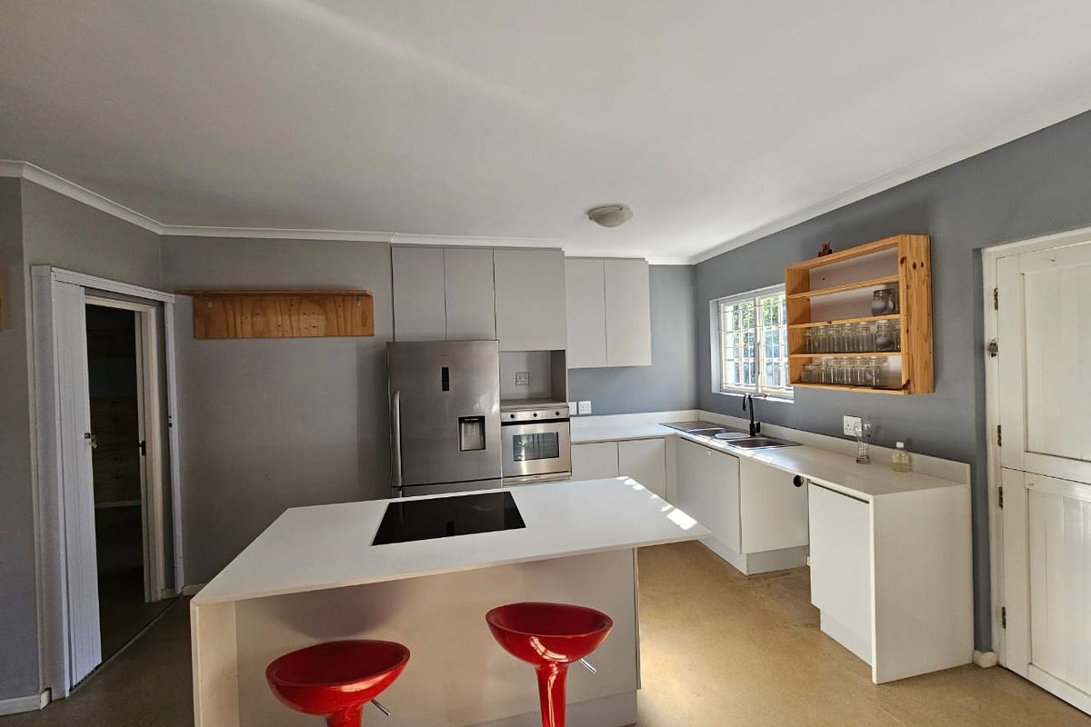 A functional kitchen featuring a central island with a built-in hob, ample cabinetry, and a double sink, offering a practical layout for daily cooking.