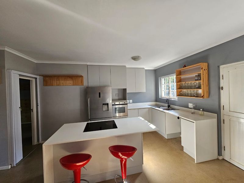 A functional kitchen featuring a central island with a built-in hob, ample cabinetry, and a double sink, offering a practical layout for daily cooking.