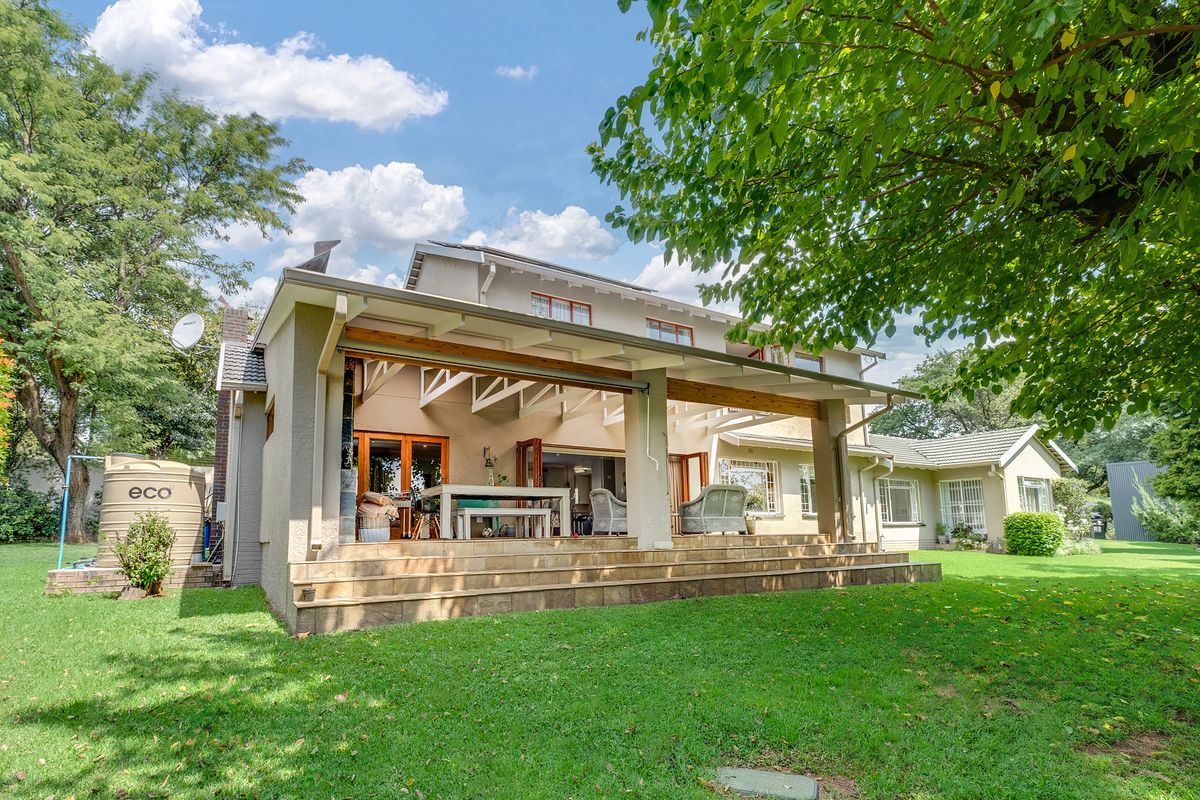 Rear view of the house featuring a spacious covered patio with timber beams, tiled flooring, and bi-fold doors leading into the main living area.