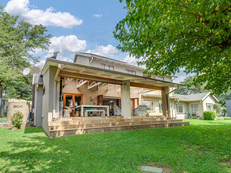 Rear view of the house featuring a spacious covered patio with timber beams, tiled flooring, and bi-fold doors leading into the main living area.