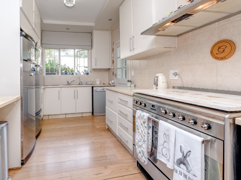 A well-maintained kitchen featuring white cabinetry, stainless steel appliances, laminate flooring, and a tiled backsplash, offering a clean and functional workspace.