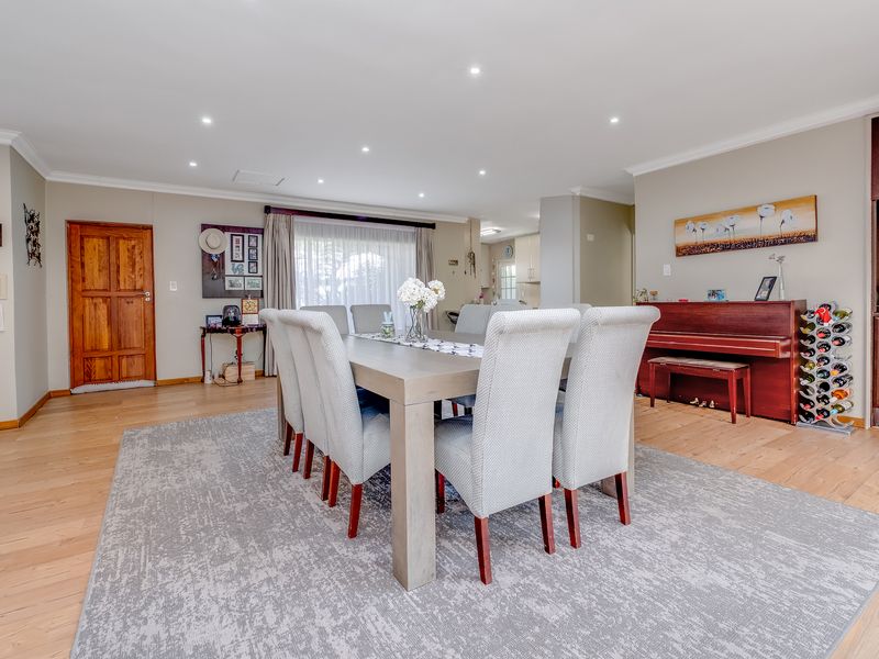 Spacious open-plan dining area featuring light timber flooring, recessed downlighting, and seamless flow into the adjacent kitchen space.