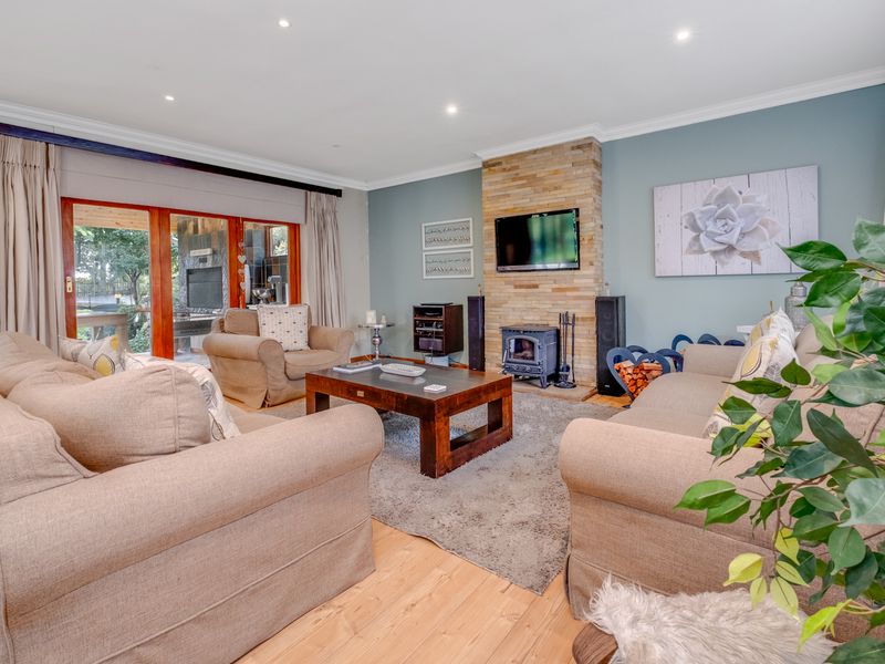 A comfortable living room featuring a stone-clad fireplace with a wood-burning stove, timber flooring, and sliding glass doors leading to an outdoor area.