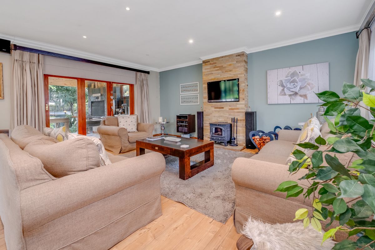 A comfortable living room featuring a stone-clad fireplace with a wood-burning stove, timber flooring, and sliding glass doors leading to an outdoor area.
