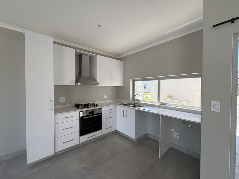 Modern kitchen featuring white built-in cabinetry, stone countertops, gas hob, electric oven, stainless steel extractor fan, and tiled flooring.