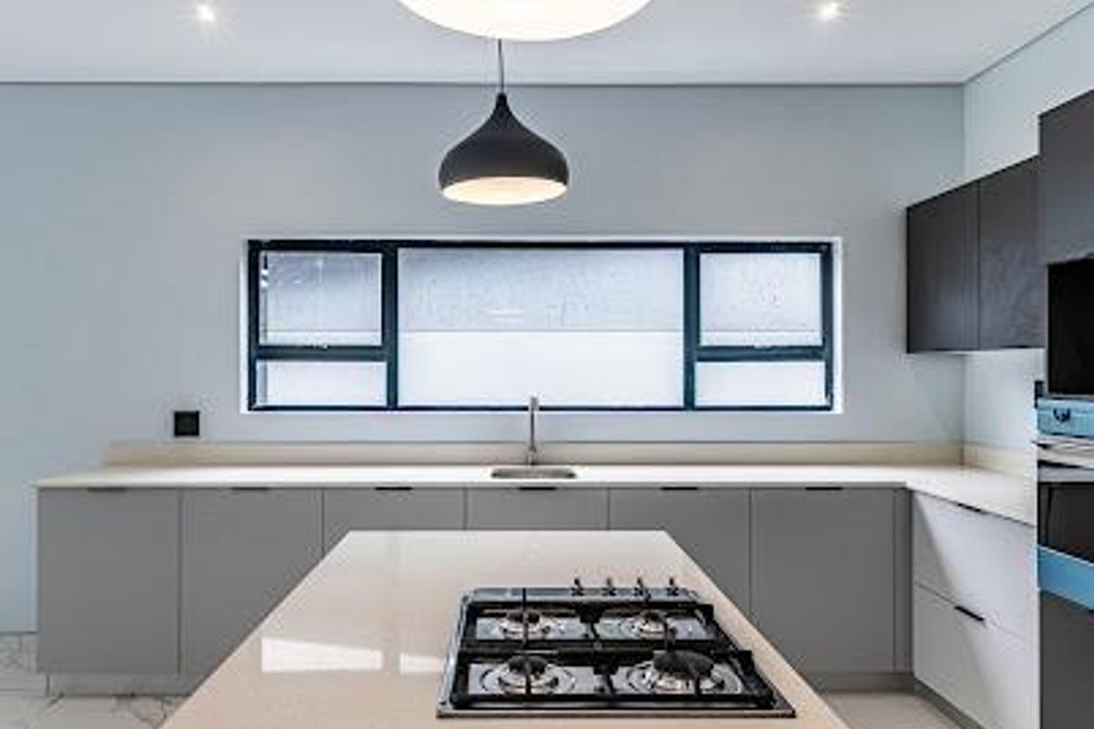 Modern kitchen featuring a central island with a gas cooktop, quartz countertops, sleek cabinetry, and high-quality finishes throughout.