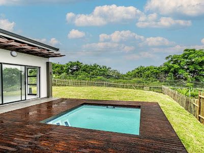 Outdoor pool area featuring timber decking, a swimming pool, and sliding glass doors leading to the main residence.
