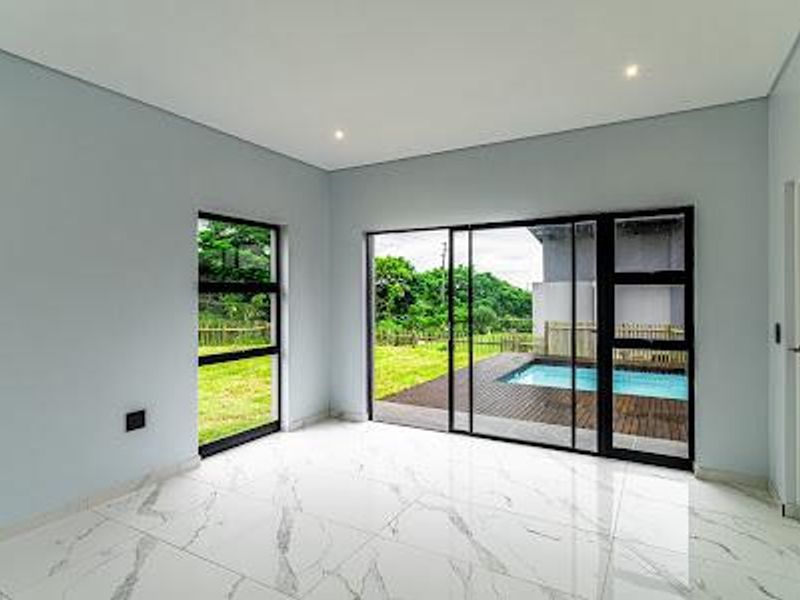 Bright, modern living area featuring large black aluminium sliding doors, marble-look floor tiles, and direct access to the outdoor pool and deck area.