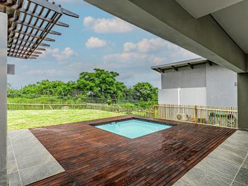 Outdoor entertainment area featuring a timber deck, a built-in plunge pool, and a pergola, overlooking a private garden with bamboo fencing.