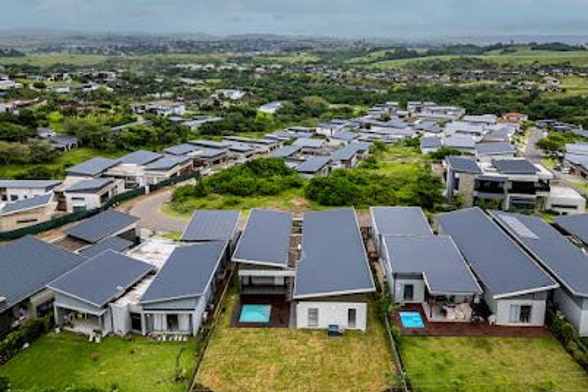 Aerial view of a residential estate featuring modern homes with pitched roofs, private swimming pools, and landscaped garden areas.