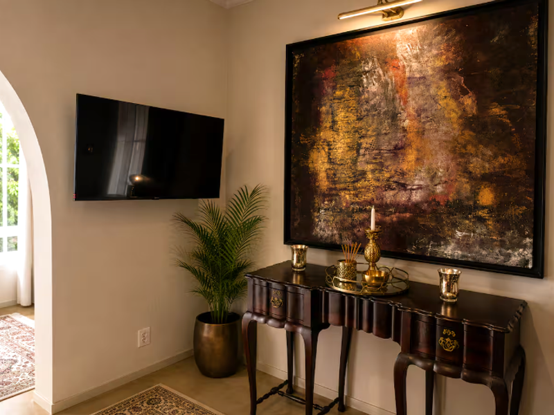 A well-maintained living area featuring a decorative archway, wall-mounted picture lighting, and neutral wall finishes.