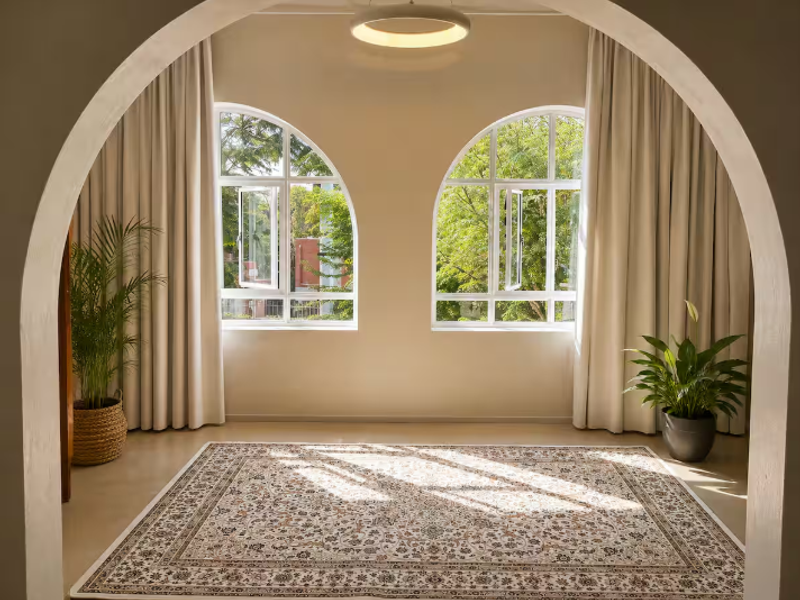 Bright living area featuring elegant arched windows, a prominent arched entryway, and neutral finishes, offering a serene and well-lit space.