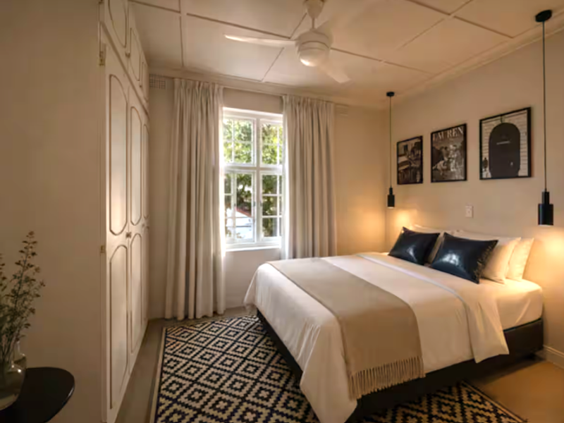 A well-maintained bedroom featuring built-in cupboards, a ceiling fan, and classic multi-pane windows that provide natural light.