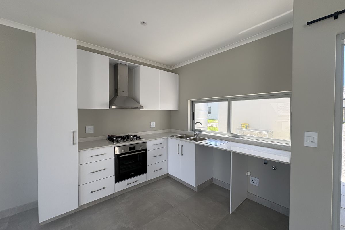 Modern kitchen featuring white built-in cabinetry, stone countertops, gas hob, electric oven, stainless steel extractor fan, and tiled flooring.