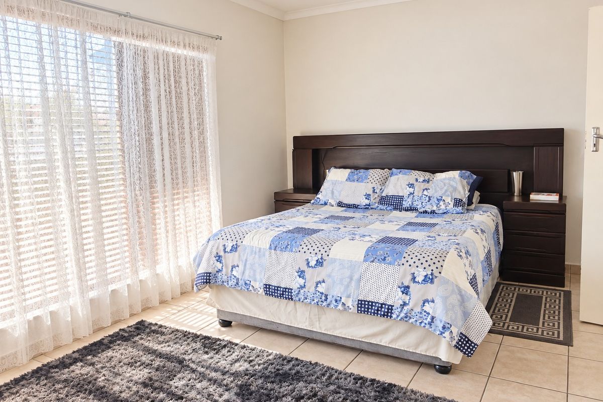 A well-lit bedroom featuring tiled flooring and a built-in dark wood headboard with integrated bedside tables.
