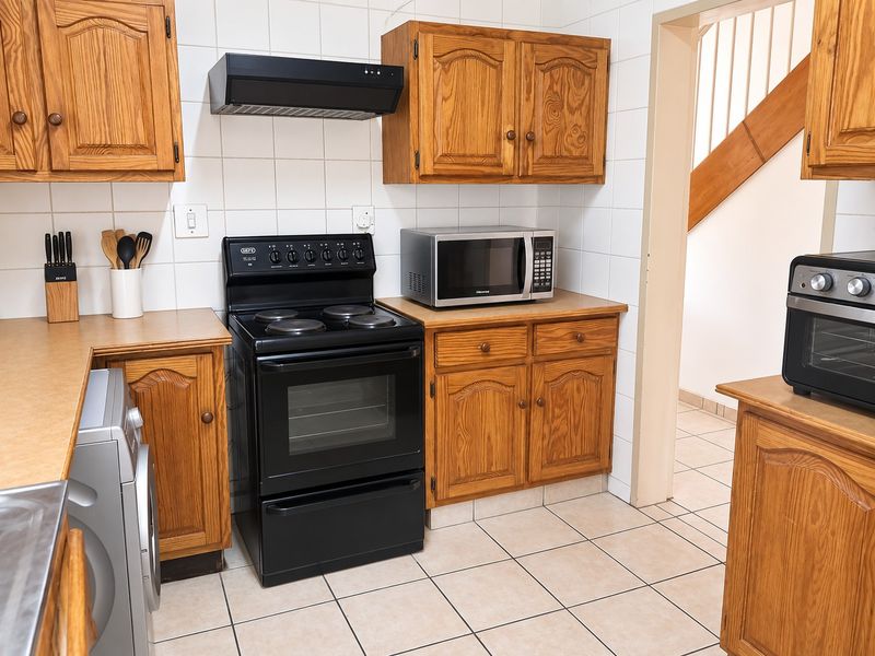 A functional kitchen featuring traditional wooden cabinetry, tiled backsplash, and a freestanding stove, offering a classic layout with potential for modern updates.