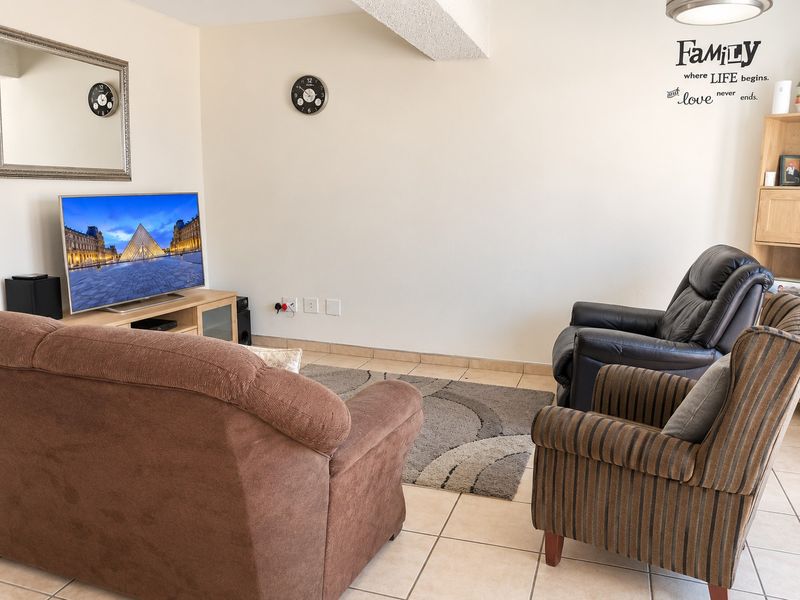 A functional living room featuring tiled flooring and a textured ceiling beam, providing a neutral base for interior updates.