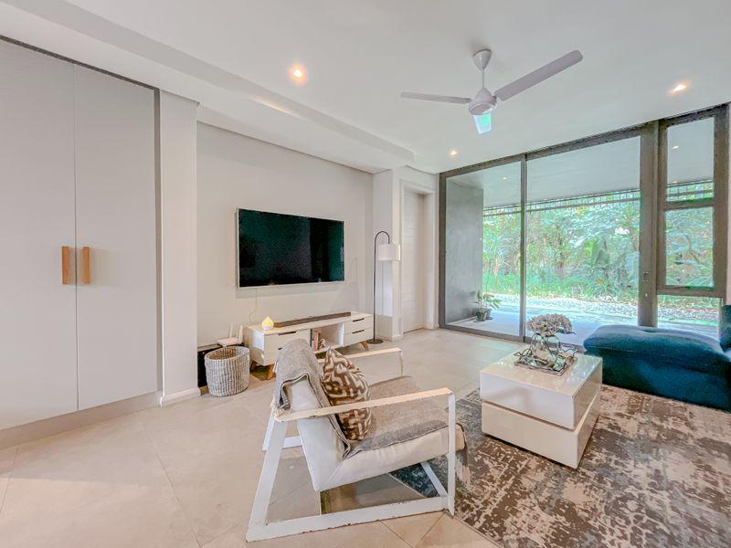 Modern living room featuring tiled flooring, recessed lighting, a ceiling fan, and large sliding glass doors providing access to an outdoor area.