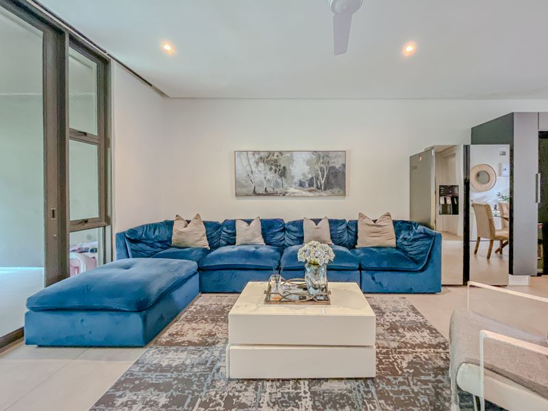 Modern living room featuring tiled flooring, recessed lighting, a ceiling fan, and large sliding glass doors providing access to the outdoor area.