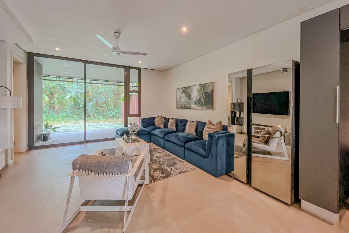 Spacious living room featuring large sliding glass doors that provide natural light and access to the outdoor area, complemented by modern tiled flooring.