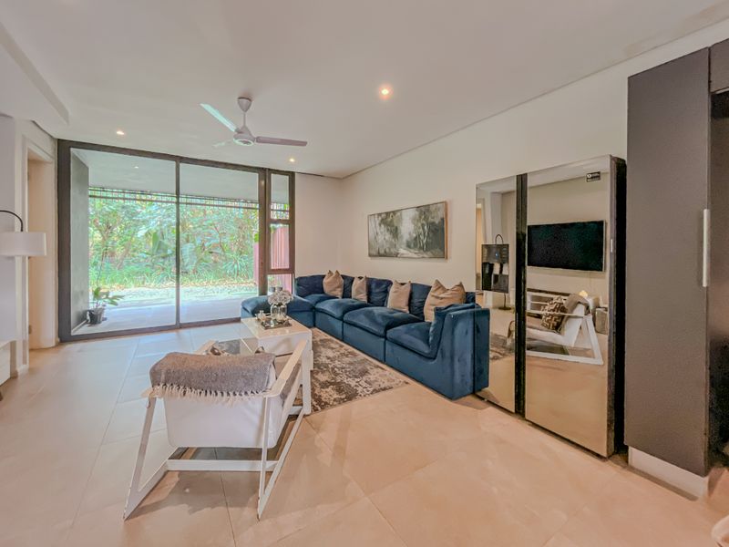 Spacious living room featuring large sliding glass doors that provide natural light and access to the outdoor area, complemented by modern tiled flooring.