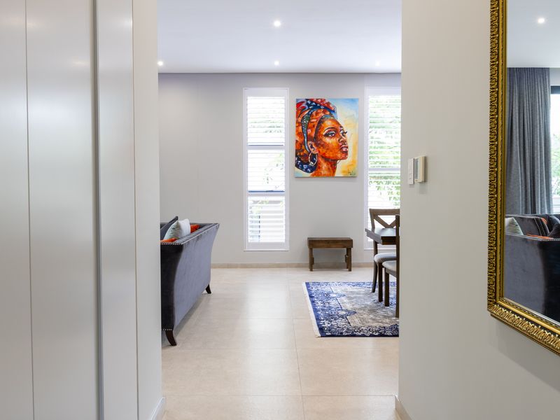 A bright open-plan living and dining area featuring neutral tiled flooring, recessed lighting, and plantation shutters, offering a clean and modern aesthetic.