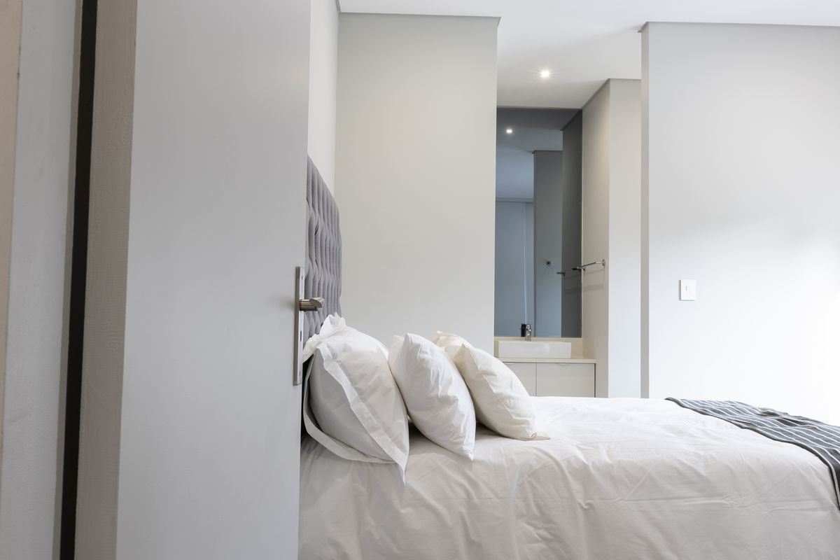 Modern bedroom featuring a neutral color palette, recessed lighting, and an integrated vanity area with a basin.