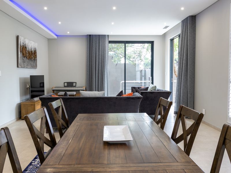 Modern open-plan living and dining area featuring tiled floors, recessed lighting, and large sliding glass doors leading to an outdoor space.