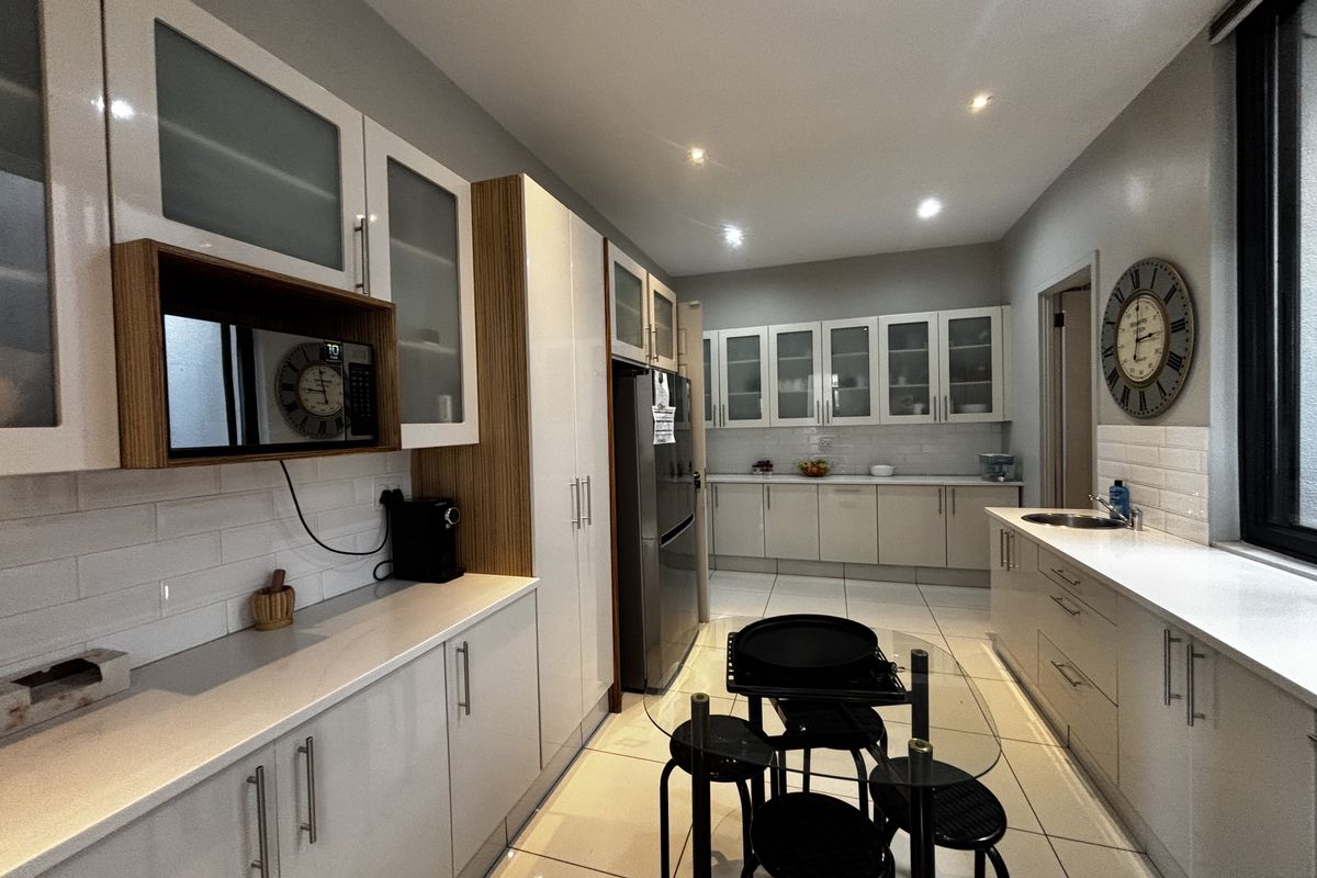 Modern kitchen featuring white cabinetry, quartz countertops, subway tile backsplash, recessed lighting, and tiled flooring in a clean, well-maintained layout.