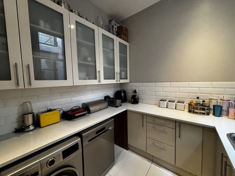 A modern kitchen featuring white subway tile backsplash, sleek quartz countertops, frosted glass upper cabinets, and integrated appliances.