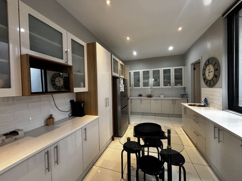 Modern kitchen featuring white cabinetry, quartz countertops, subway tile backsplash, recessed lighting, and tiled flooring in a clean, well-maintained layout.
