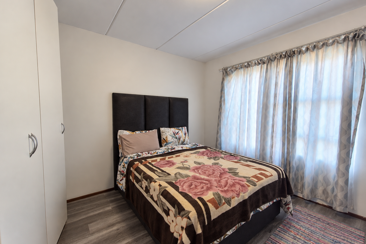 A well-maintained bedroom featuring modern laminate flooring, a built-in wardrobe, and neutral wall finishes, providing a clean and functional living space.