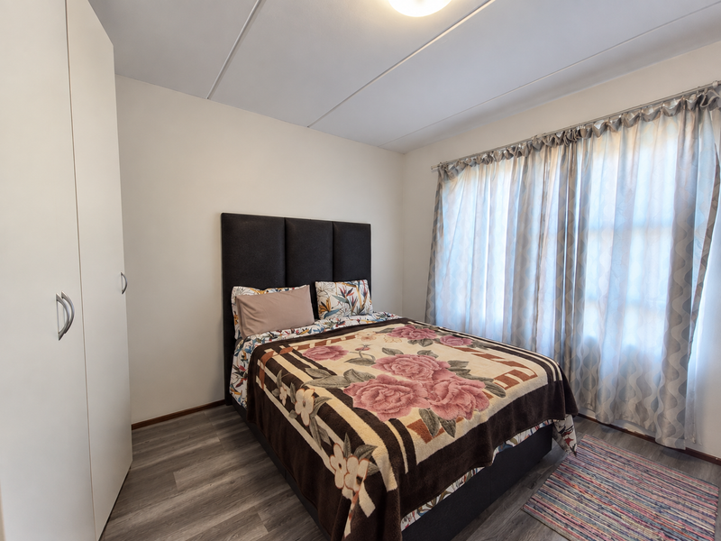 A well-maintained bedroom featuring modern laminate flooring, a built-in wardrobe, and neutral wall finishes, providing a clean and functional living space.