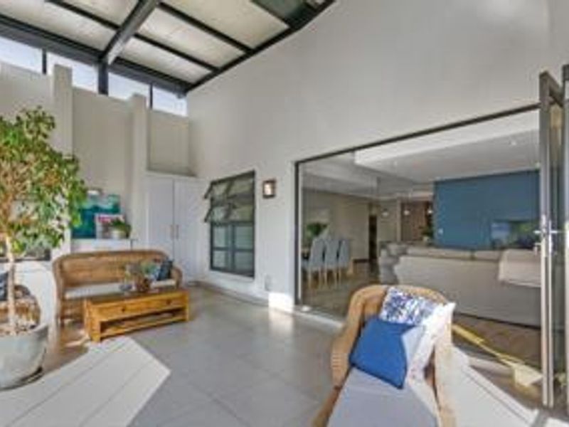 A spacious covered patio featuring tiled flooring, a skylight, and bi-fold doors that provide seamless access to the interior living area.