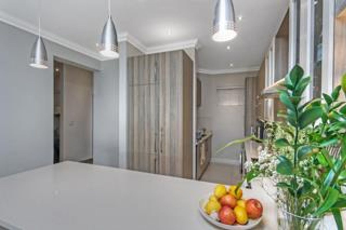 Modern kitchen featuring sleek cabinetry, quartz countertops, integrated appliances, and stylish pendant lighting, creating a clean and functional culinary space.