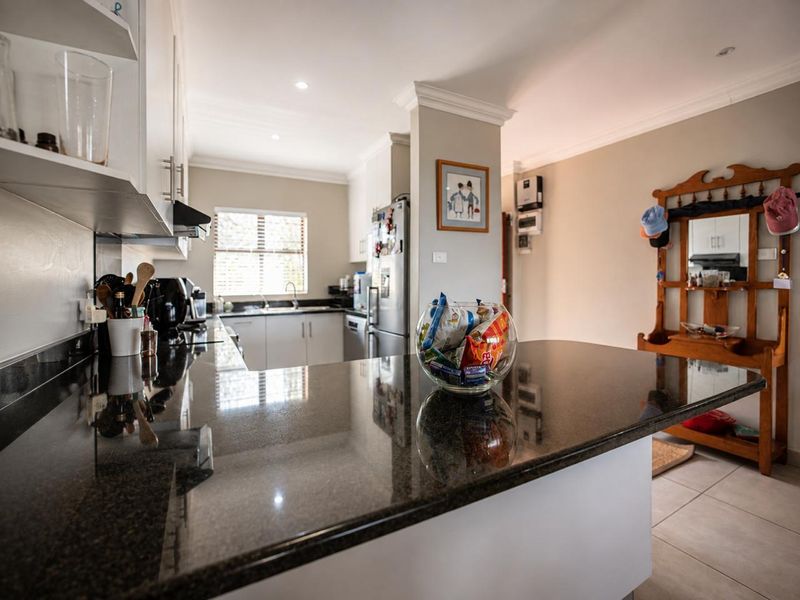 A well-maintained kitchen featuring dark granite countertops, white cabinetry, and tiled flooring, offering a clean and functional workspace.