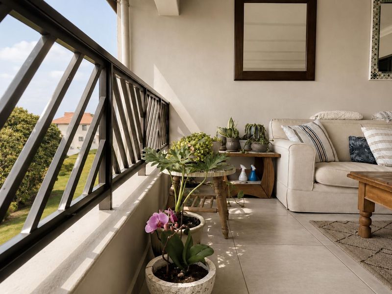 A covered balcony featuring tiled flooring and a metal balustrade, offering an outdoor living space with views of the surrounding area.