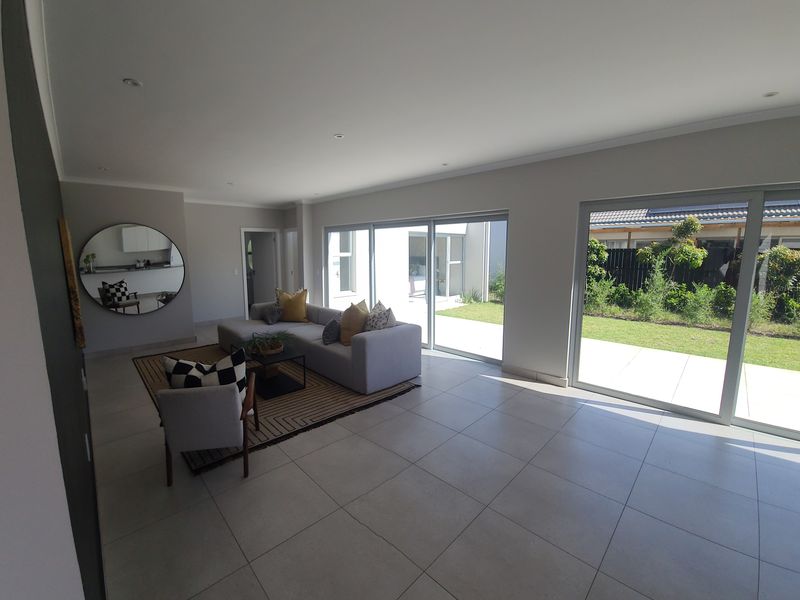 Spacious living area featuring large format floor tiles, recessed downlighting, and expansive sliding glass doors providing seamless access to the garden.